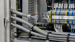 Cables blindados dentro de un gabinete eléctrico industrial para protección contra interferencias electromagnéticas.